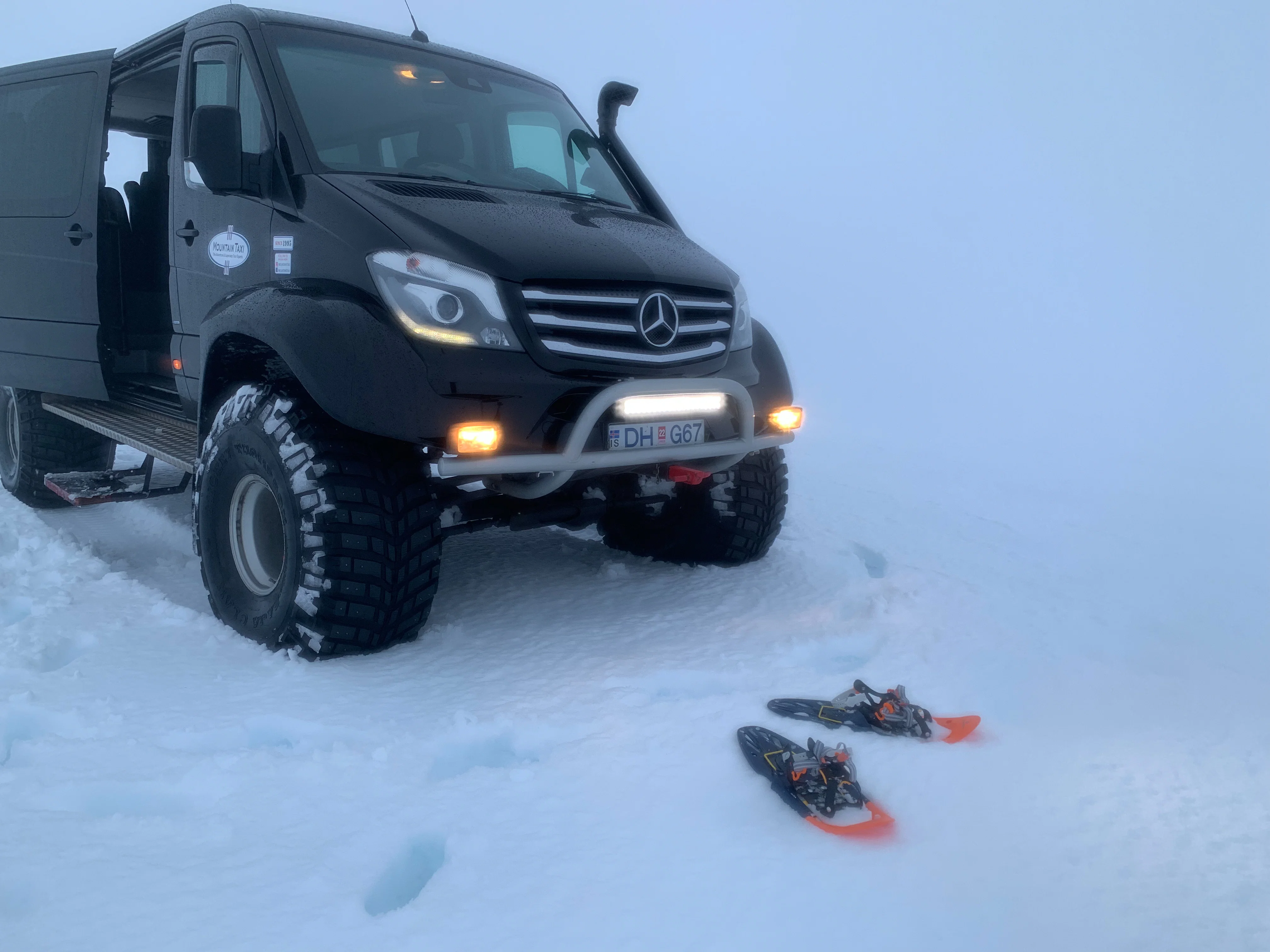 Super Jeep parked in the snow with snowshoes on the ground, ready for a winter adventure.